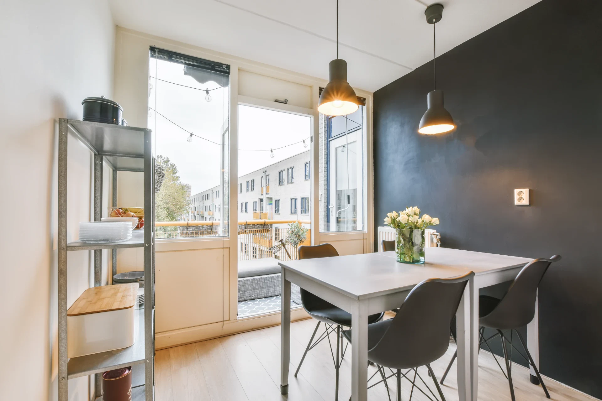 Moderne spisestue med store vinduer, sort væg og enkel bordindretning.