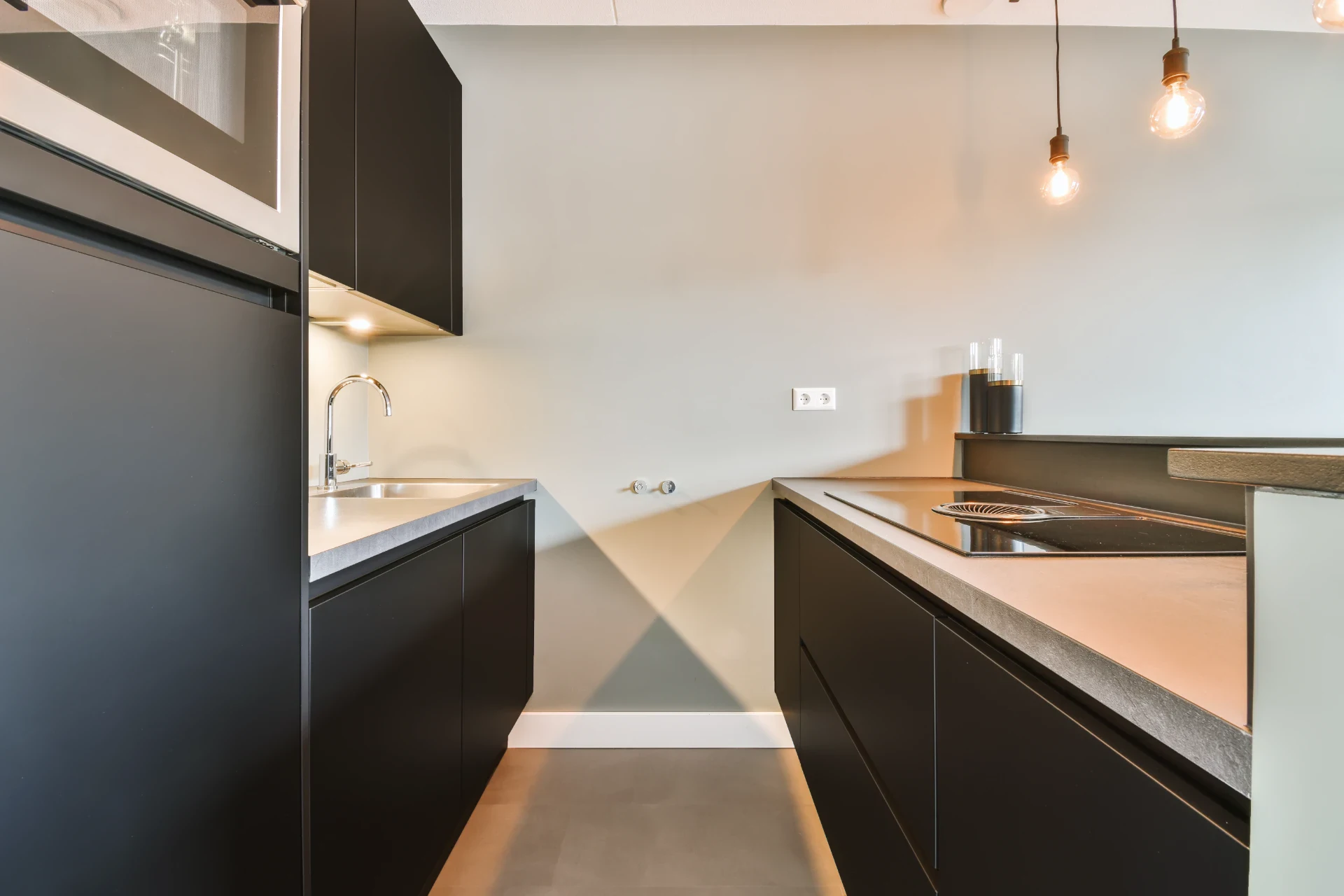 Moderne køkken med sorte skabe og bordplade, minimalistisk design.