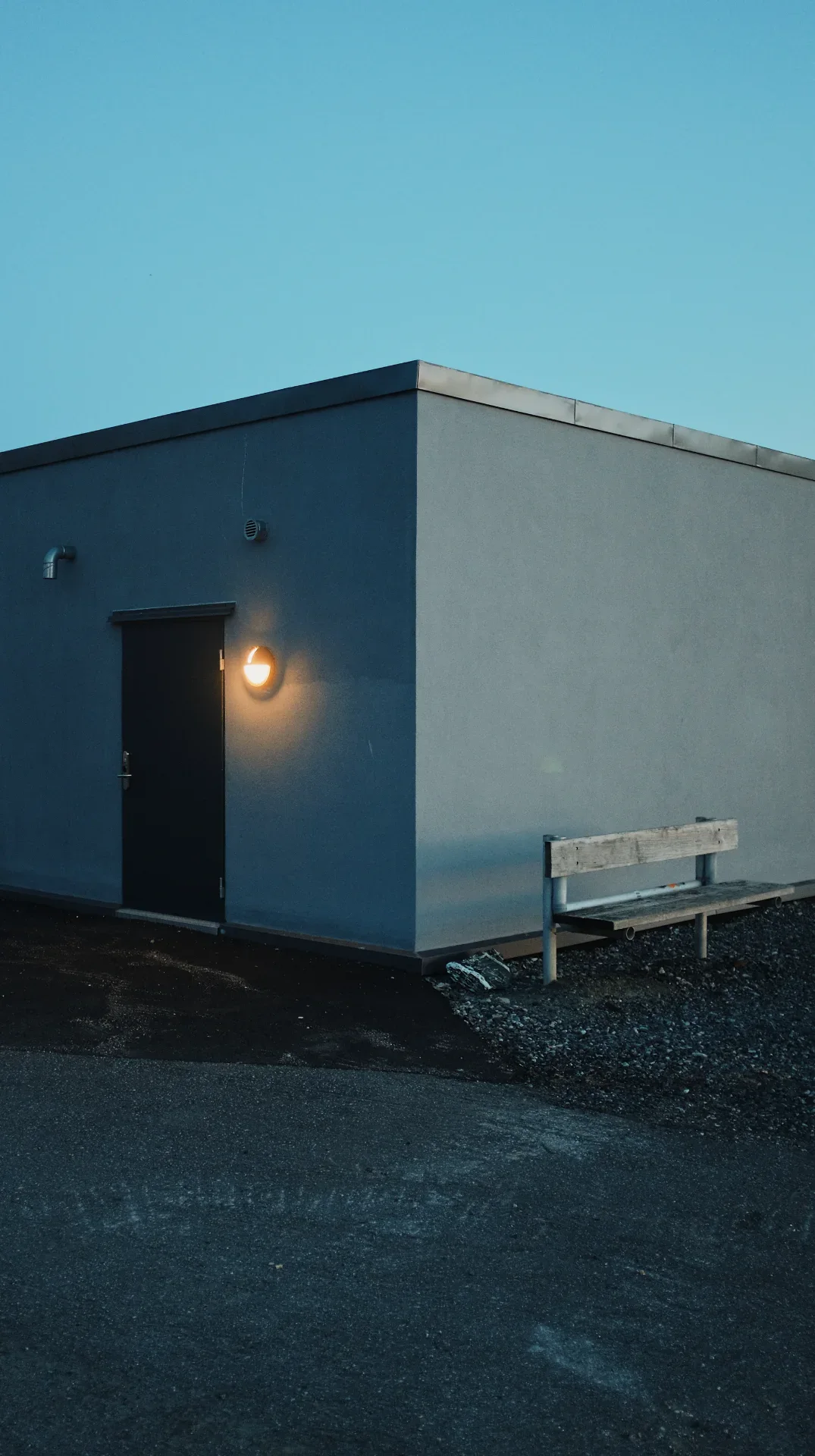 Udendørs væglampe oplyser indgangsområde på en bygning.