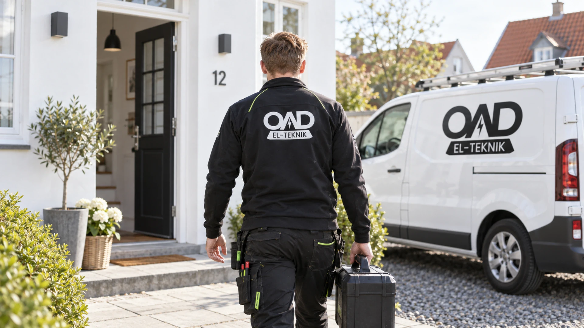 Elektriker fra OAD El-teknik arbejder udendørs foran en bolig.